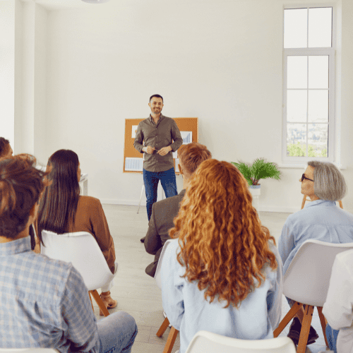 Un formateur homme présente son sujet devant une assemblée de professionnels suivant une formation dédiée.